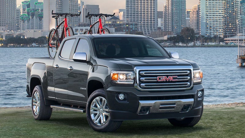 A 2018 GMC Canyon is positioned in front of a bustling city